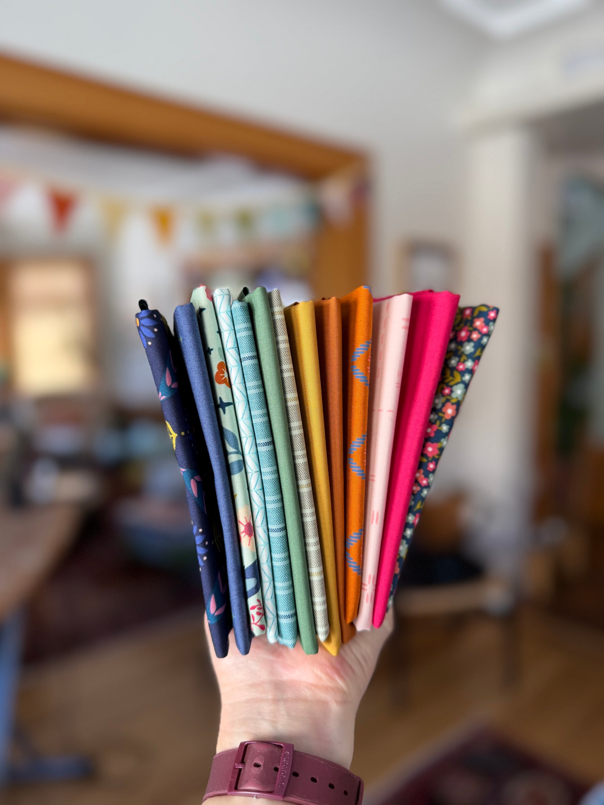 Hand holding a bundle of rainbow colored fabrics with a blurred background