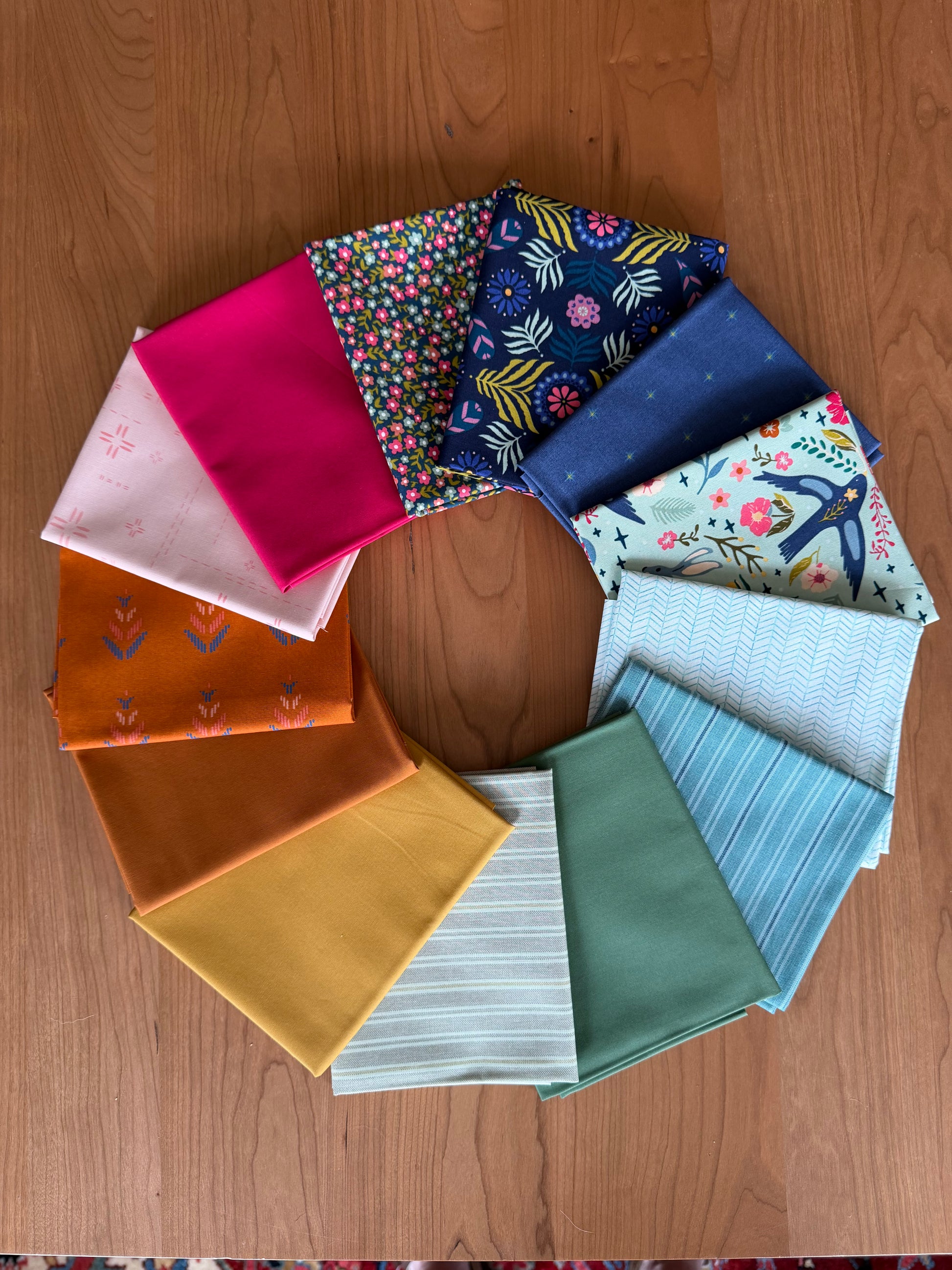 Collection of colorful fabric samples arranged in a circular pattern on a wooden surface.