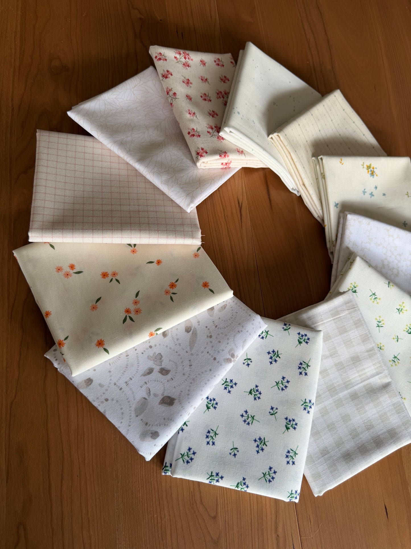 Collection of patterned fabrics arranged in a circular formation on a wooden surface.