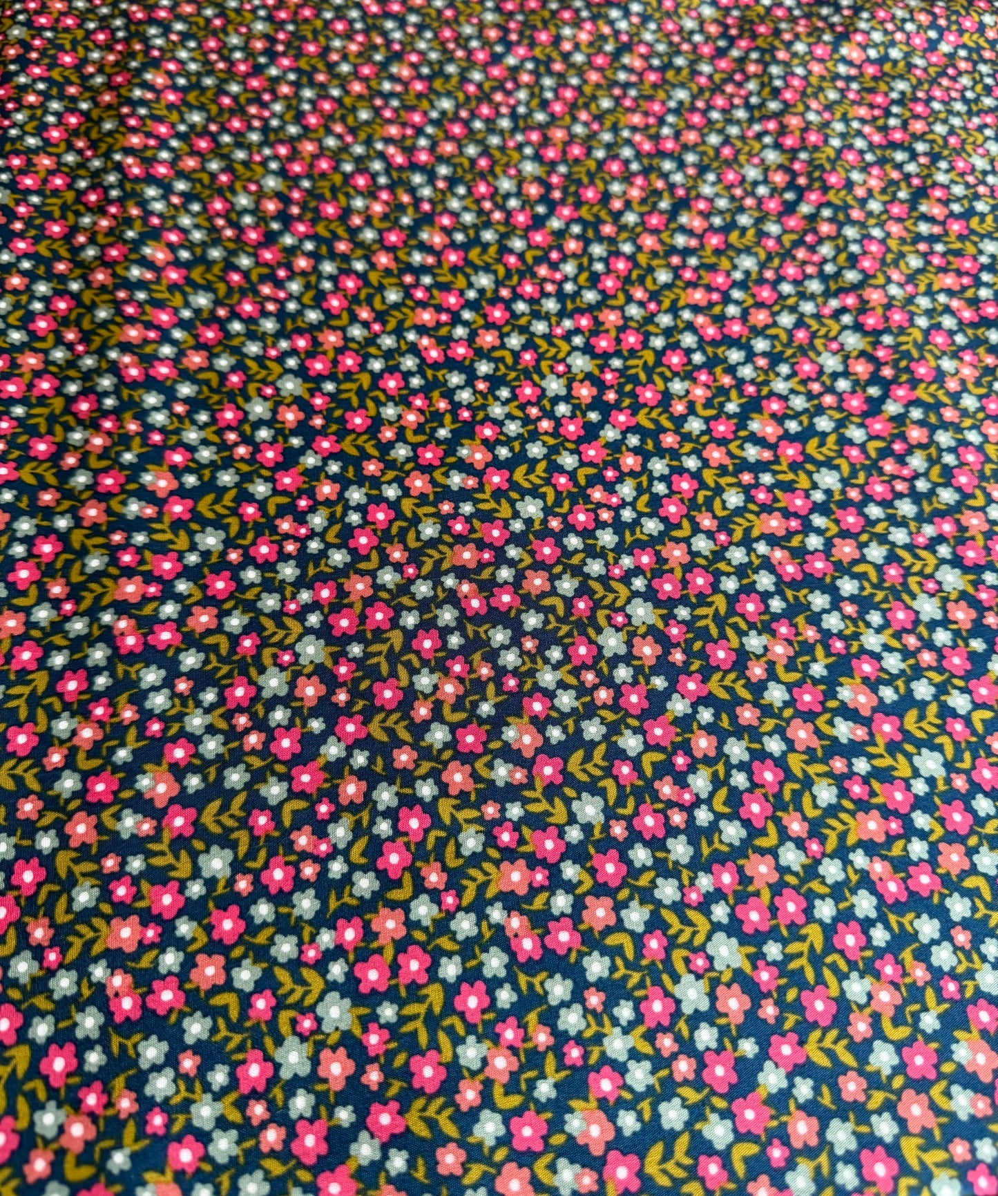 Floral patterned fabric with small pink flowers on a dark blue background